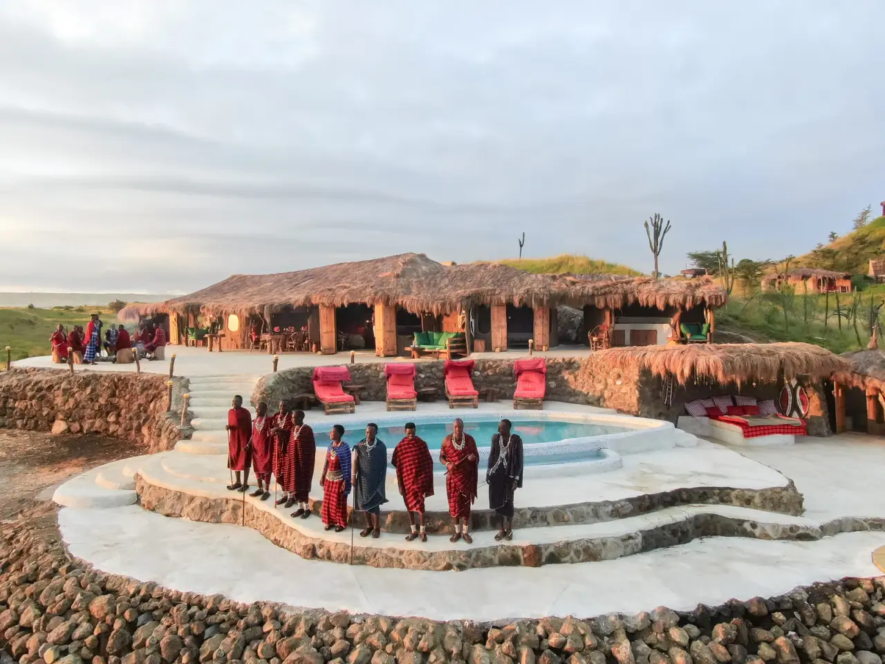 Maasai warriors in traditional red shuka beside the pool terrace at Africa Amini Original Maasai Lodge on West Kilimanjaro