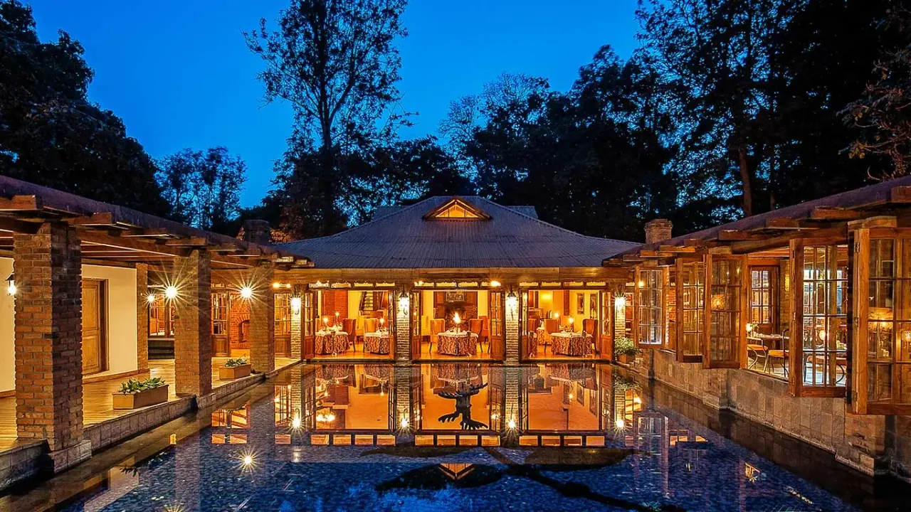 Main lodge building at Arusha Coffee Lodge lit up at night around a reflecting courtyard pool