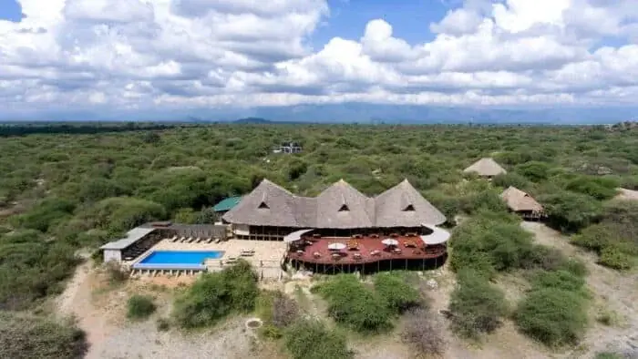 Aerial view of Burunge Tented Lodge's thatched main building, pool and bush surroundings near Tarangire National Park