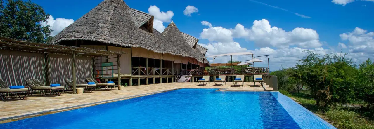 Swimming pool and sun loungers beside the thatched main lodge at Burunge Tented Lodge