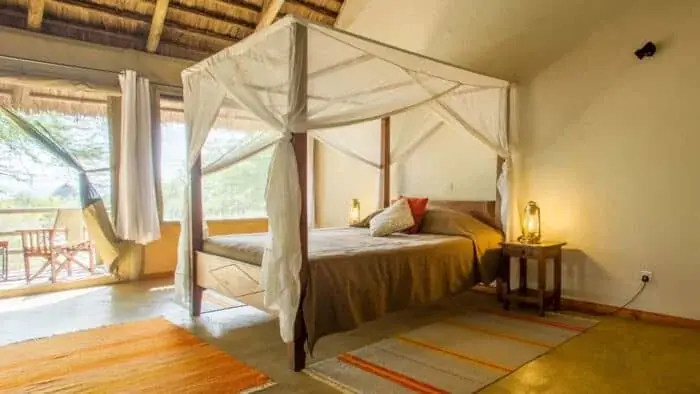 Canvas tent bedroom at Burunge Tented Lodge with a draped four-poster bed and hammock on the private balcony