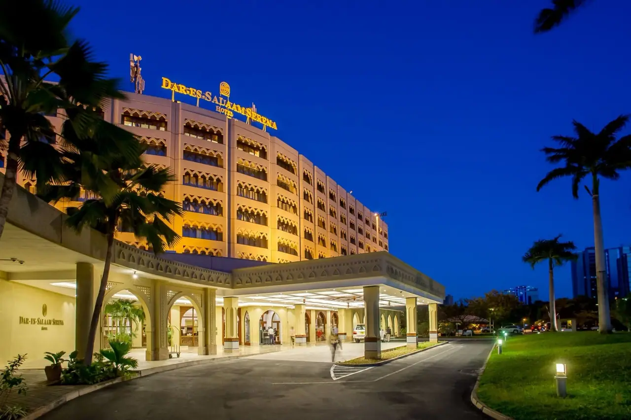 Illuminated porte-cochere entrance of Dar es Salaam Serena Hotel at night with palm trees lining the driveway