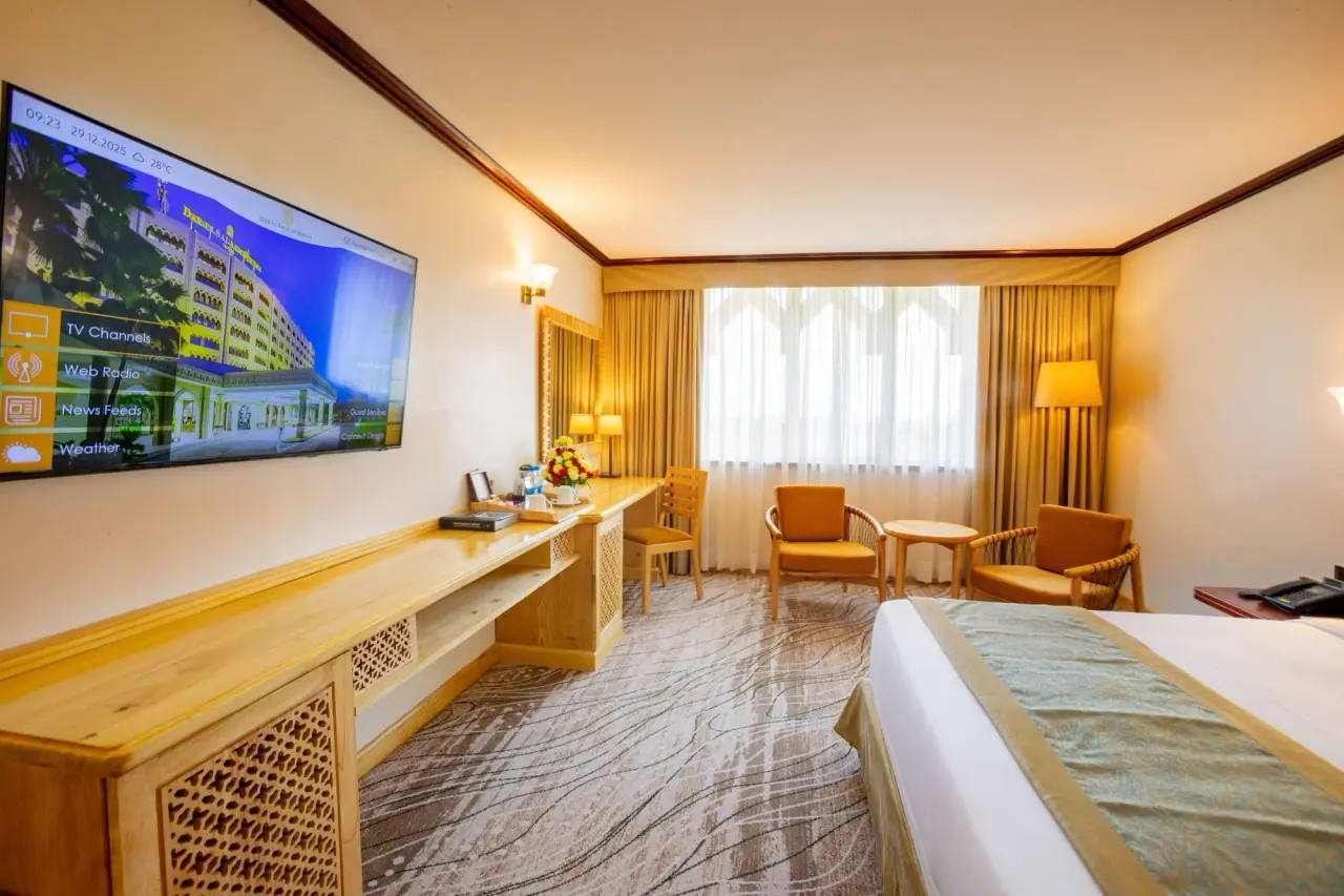 Guest room with a smart TV welcome screen and gold-trimmed bedding at Dar es Salaam Serena Hotel