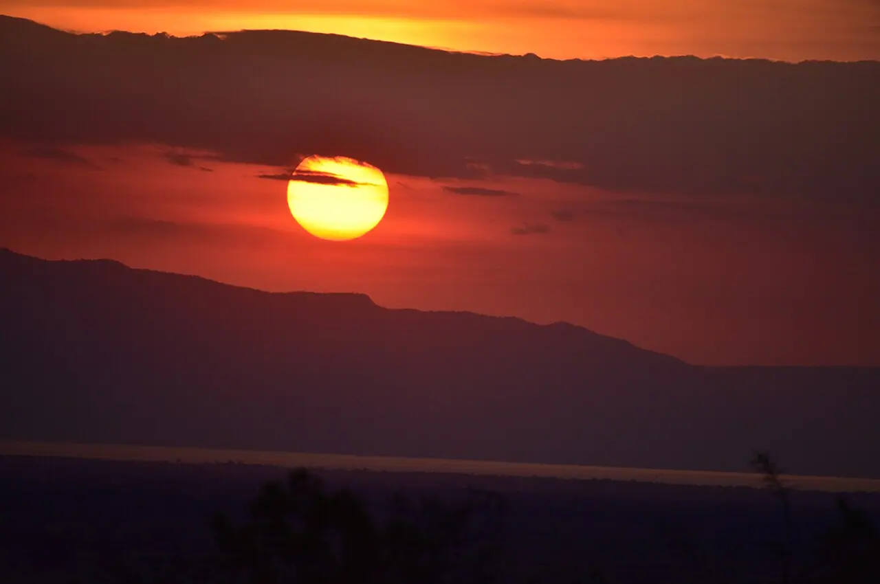 The sun setting orange behind a distant ridge, seen from the lodge