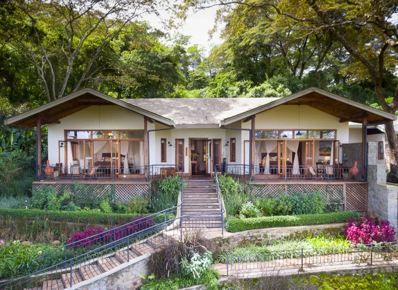 Twin-gabled cottage exterior with garden steps and bougainvillea at Gibb's Farm below the Ngorongoro Highlands