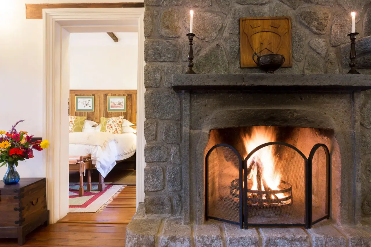 Stone fireplace lounge with candlelight opening onto a guest bedroom at Gibb's Farm