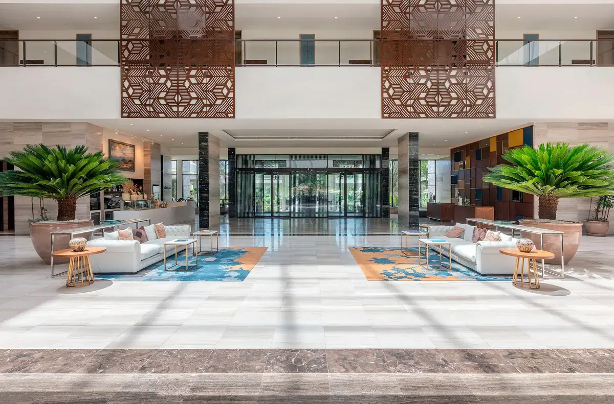 Spacious marble-floored lobby at Gran Melia Arusha with white lounge seating and carved wooden screens