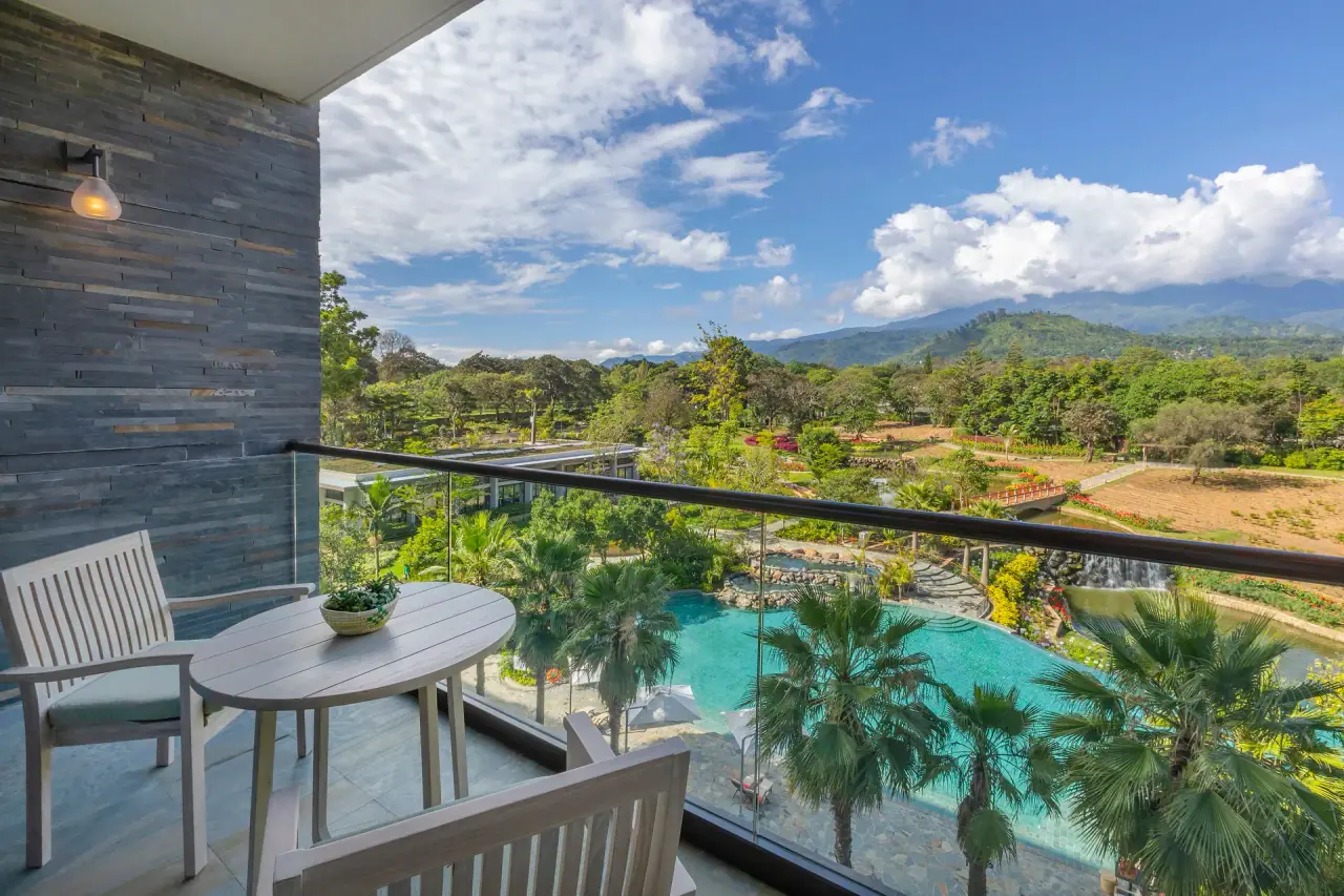 Guest room balcony at Gran Melia Arusha looking down over the resort pool and gardens toward the Arusha hills