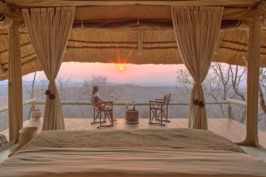Guest at Ikuka Camp relaxing on a private deck at sunset overlooking the Ruaha wilderness from the bedroom