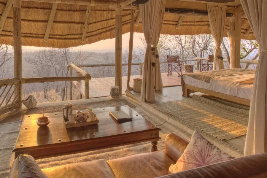 Open-sided thatched lounge at Ikuka Camp with leather sofas and sweeping views over the Ruaha hills