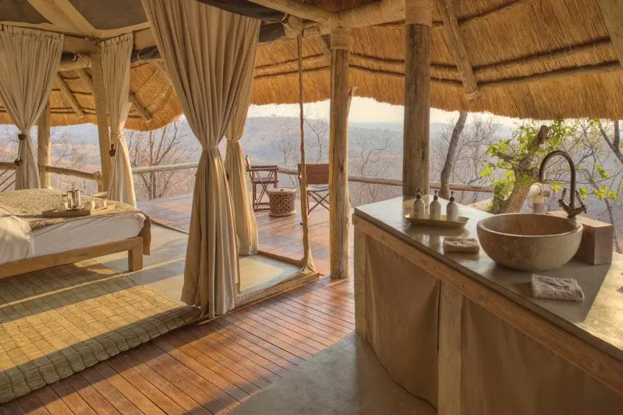 Open-air stone-basin bathroom at Ikuka Camp with a view over the Ruaha wilderness through the thatch structure