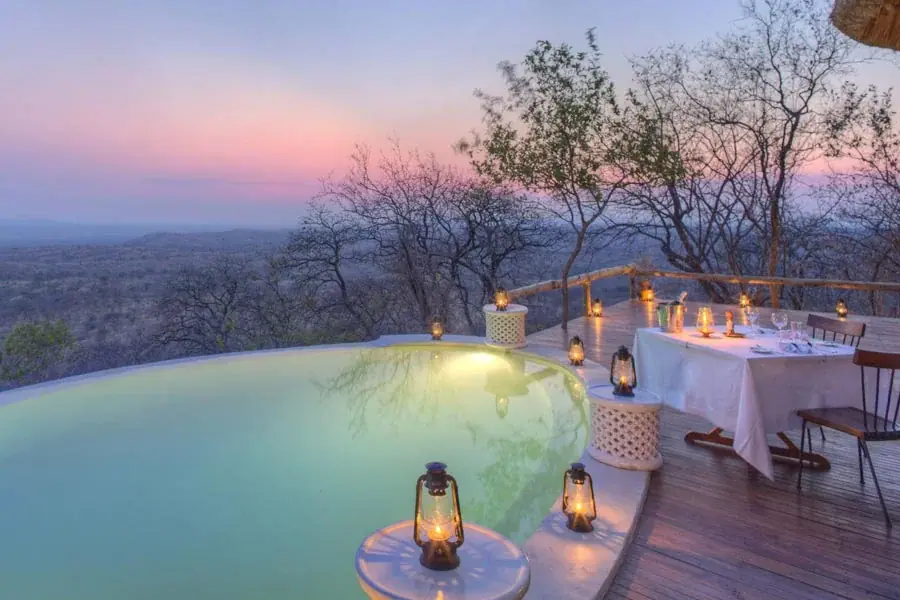 Private plunge pool and lantern-lit dinner table at Ikuka Camp overlooking the Ruaha landscape at dusk