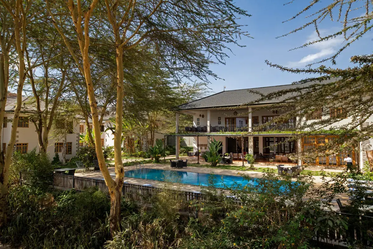 Kahawa House guesthouse exterior and swimming pool framed by acacia trees on the coffee estate