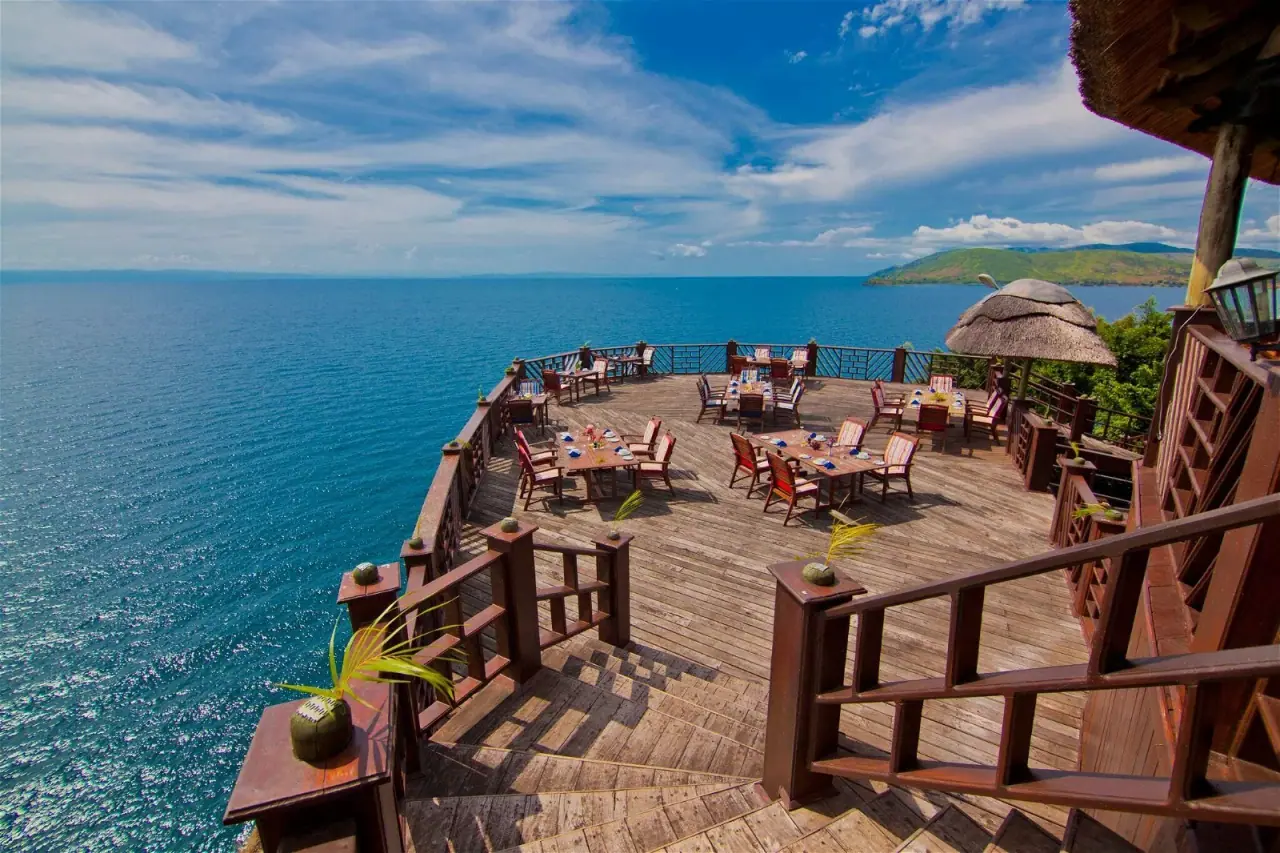 Cliffside dining deck at Kigoma Hilltop with tables set overlooking the blue waters of Lake Tanganyika