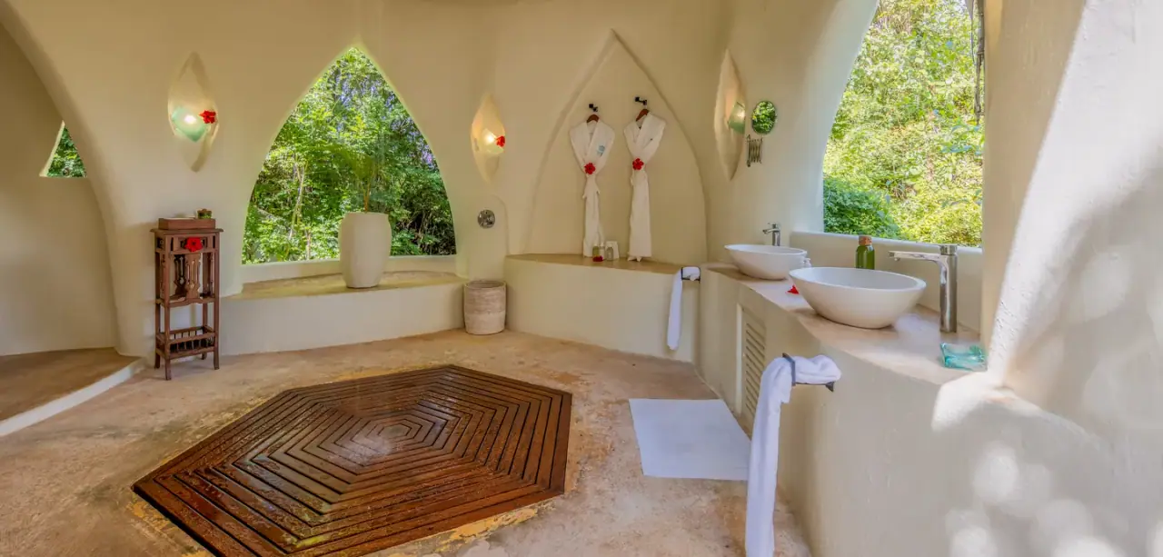Domed open-air bathroom at Kilindi Zanzibar with twin stone basins and hanging bathrobes