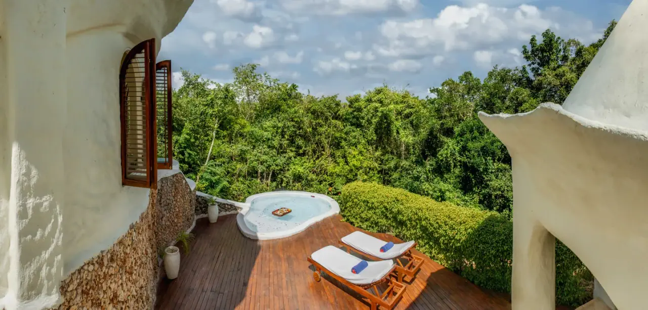 Private plunge pool on a wooden deck outside a domed pavilion at Kilindi Zanzibar, framed by forest canopy