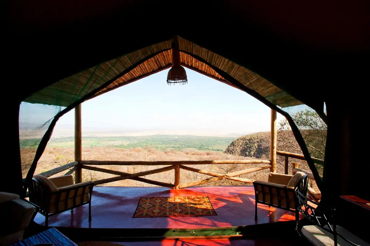 Open-air lounge tent at Kirurumu Manyara Lodge framing a sweeping view over the Lake Manyara escarpment and Rift Valley floor