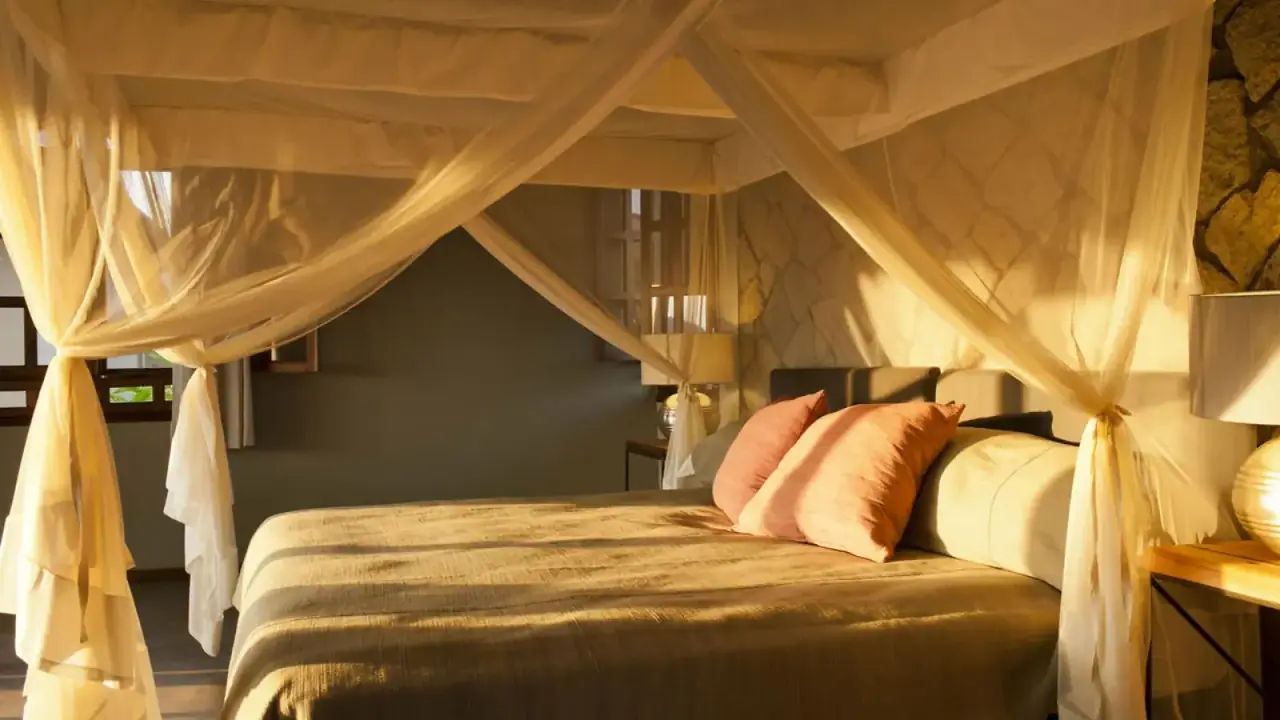 Suite bedroom at Kitela Lodge with a sheer draped canopy bed lit by warm evening light