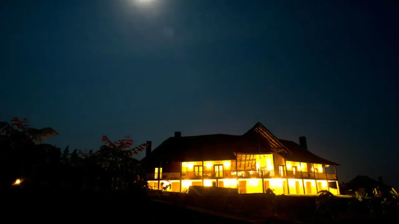 Main lodge building illuminated at night beneath a rising moon at Kitela Lodge