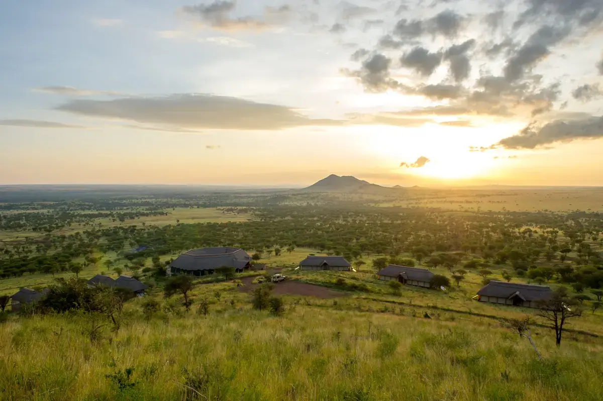 Aerial view of thatched tents at Kubukubu Tented Lodge overlooking the Serengeti plains at sunset
