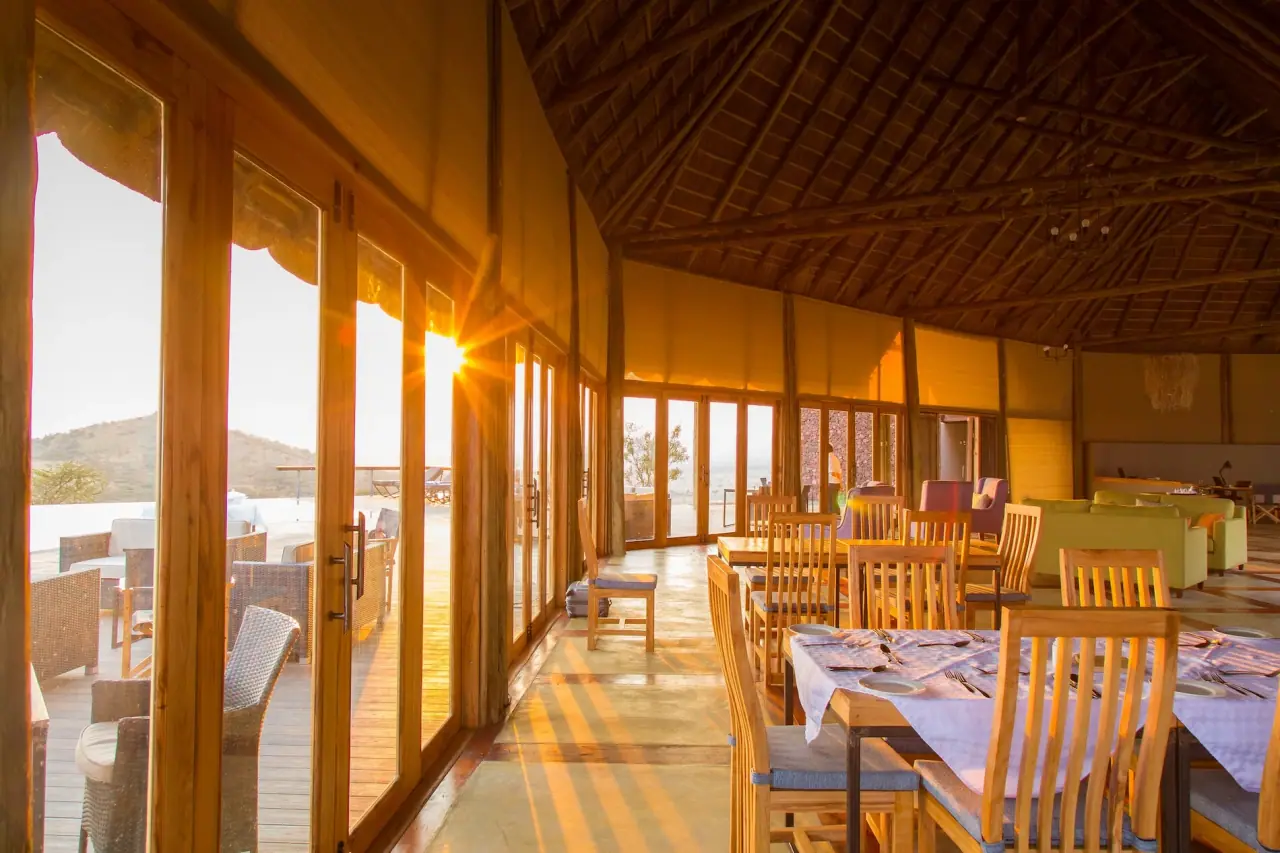Dining room corridor at Lahia Tented Lodge lit by golden sunset light through floor-to-ceiling windows