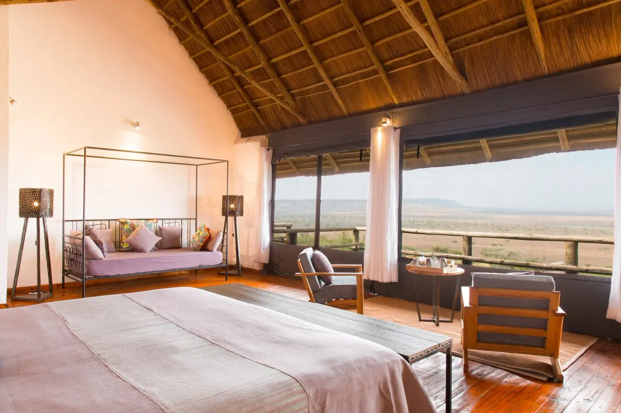 Suite bedroom at Lahia Tented Lodge with a daybed and floor-to-ceiling views of the Serengeti plains