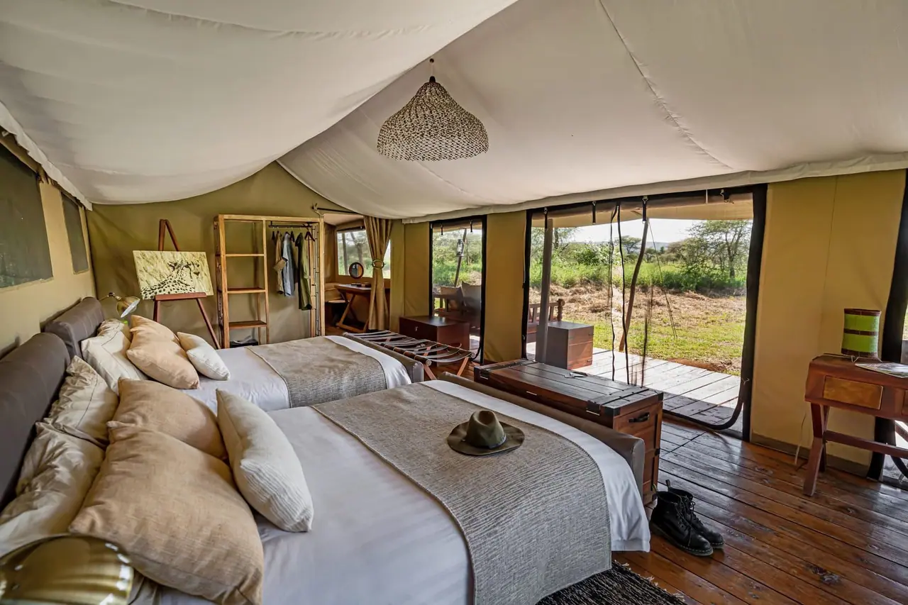 A tent bedroom with two beds and an open view of the plains