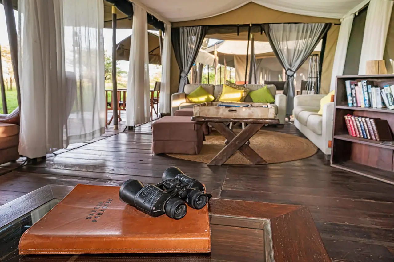 A tent lounge with a leather-bound table, binoculars and bookshelves