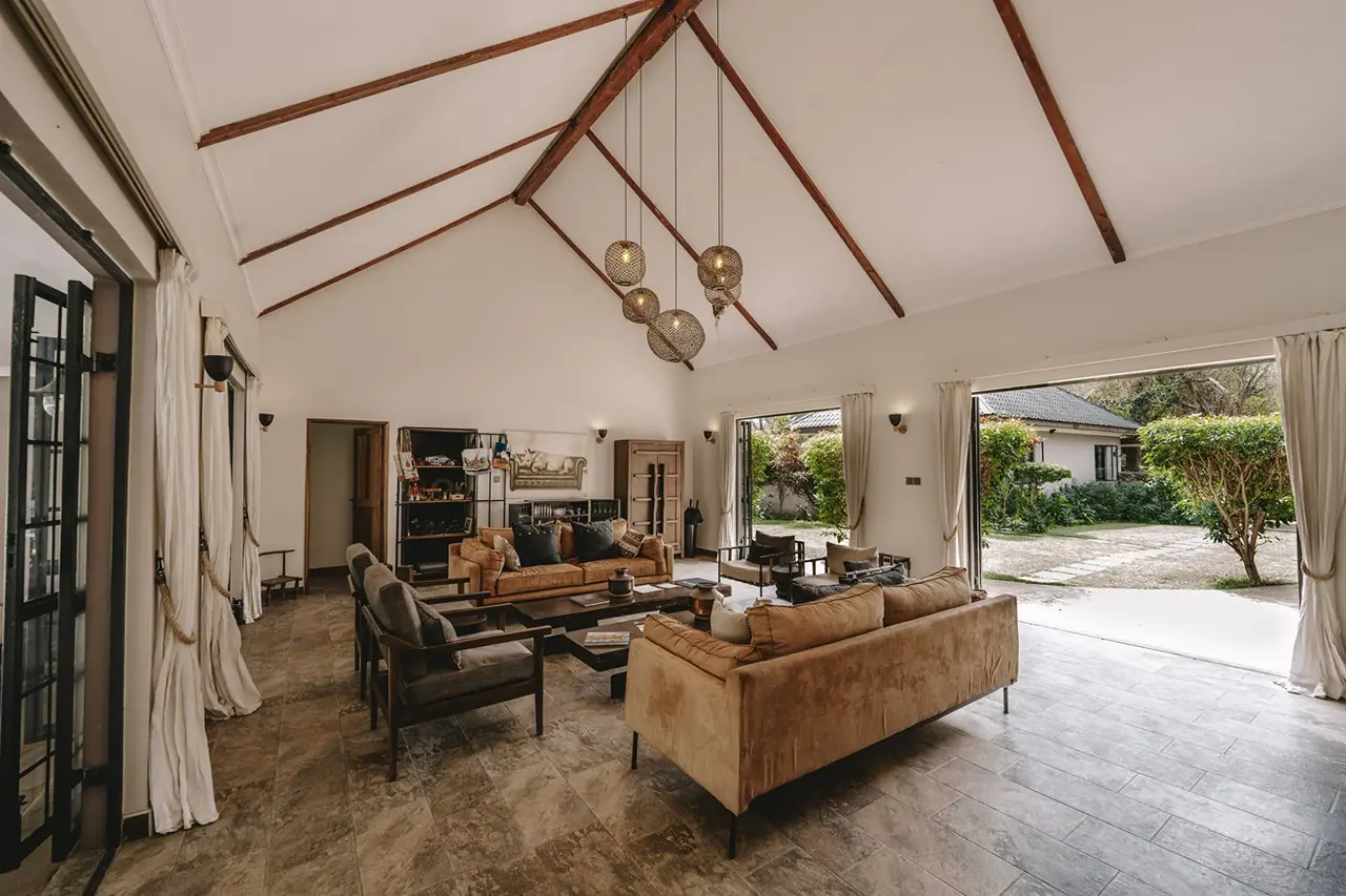 Open-plan lounge with exposed roof beams and glass doors to the garden
