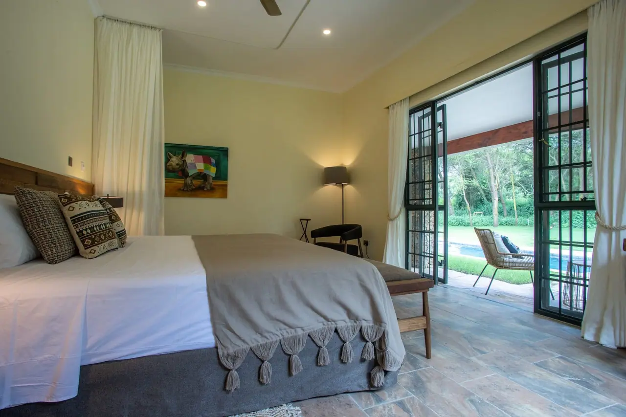 An en-suite bedroom with a white bed and doors opening to the garden