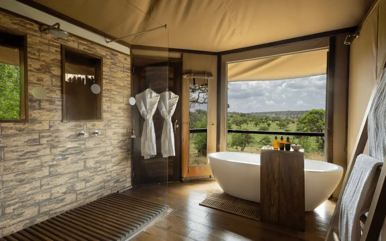 Tented suite bathroom at Lemala Kuria Hills with a freestanding tub framed by sweeping savannah views