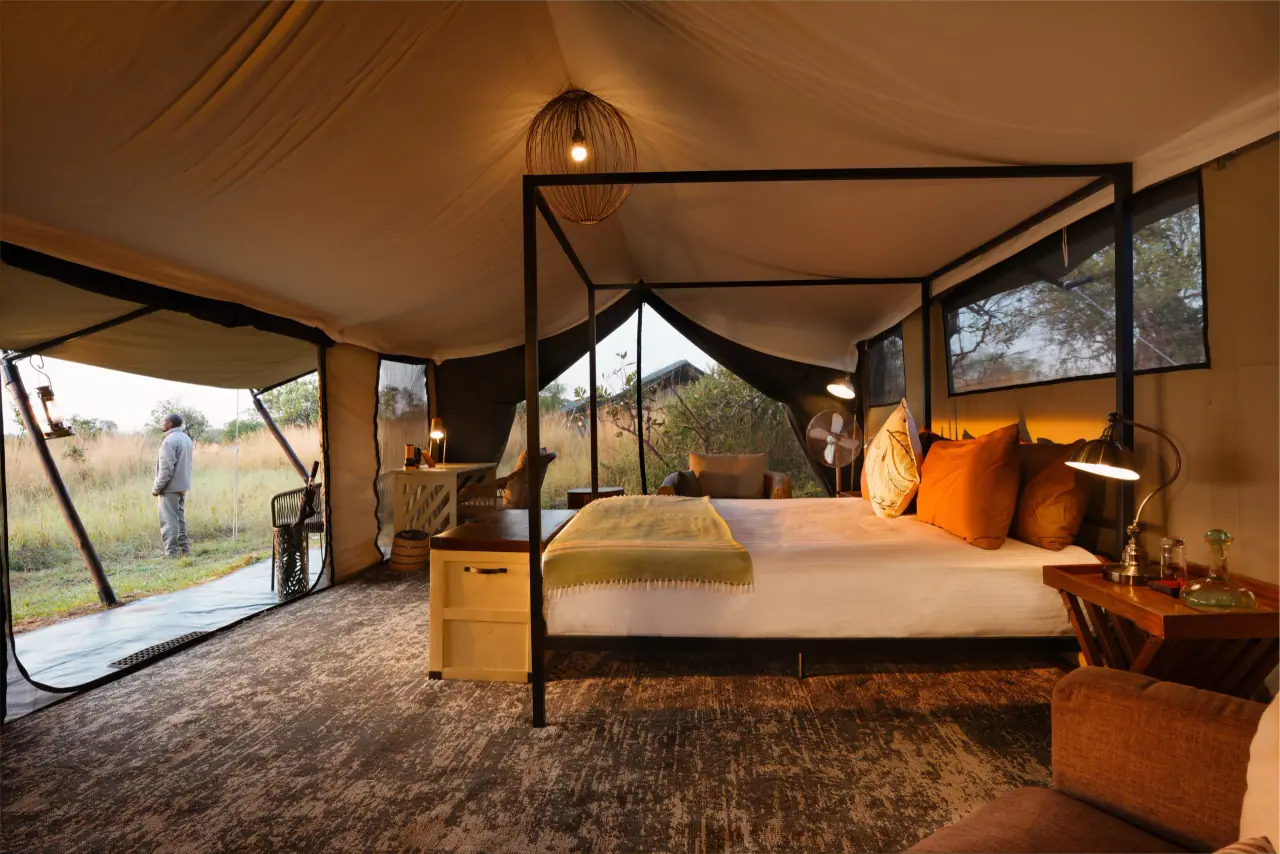 A four-poster bed inside a guest tent with the plains beyond