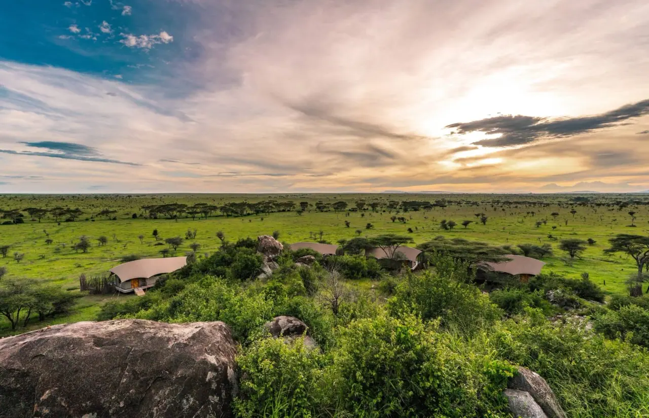 Aerial view of tented camp nestled among boulders and acacia trees on the Serengeti-Tarangire plains at sunset at Lemala Nanyukie