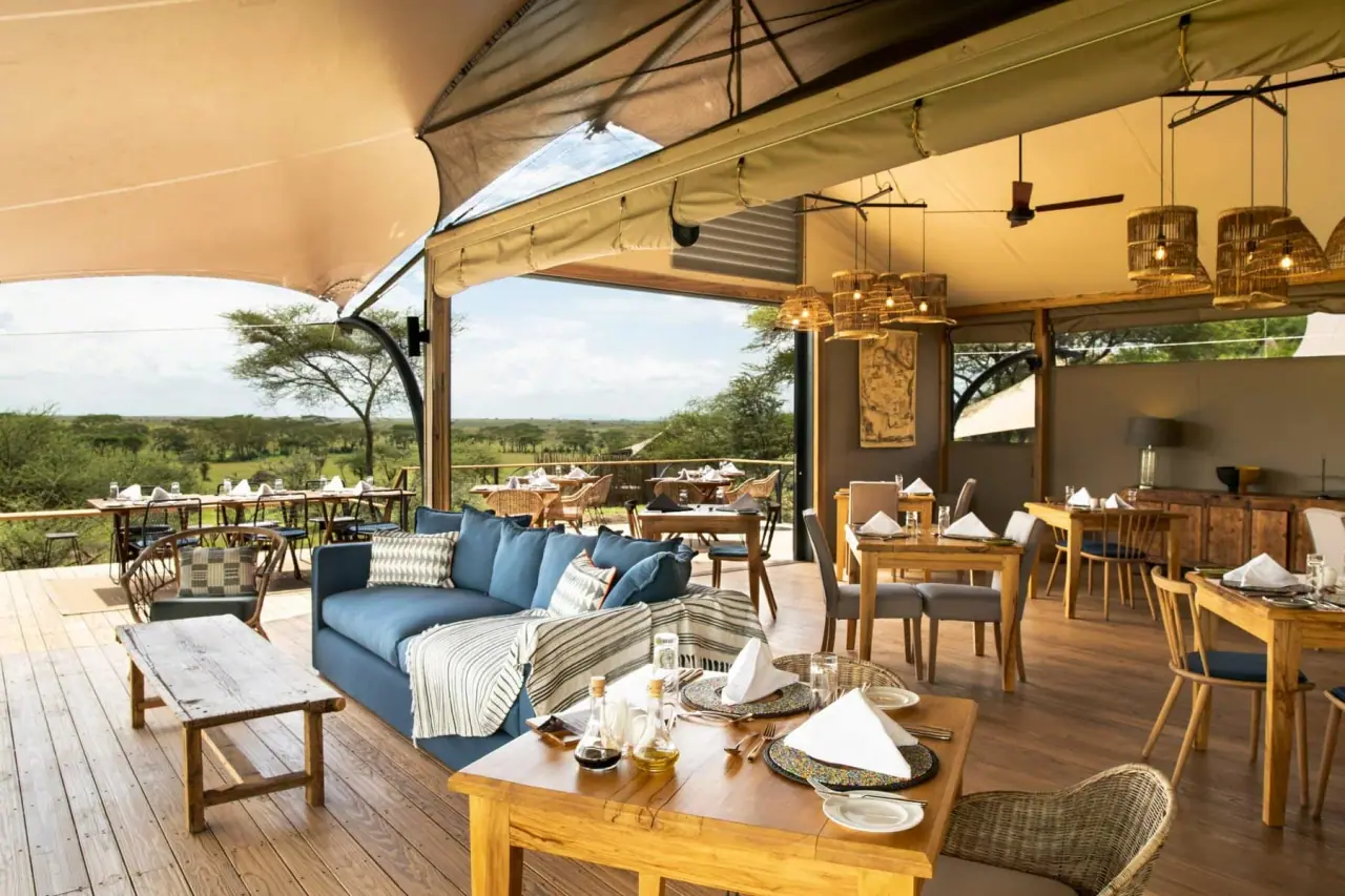 Open-sided lounge and dining deck at Lemala Nanyukie with blue sofas and views over the Tarangire plains