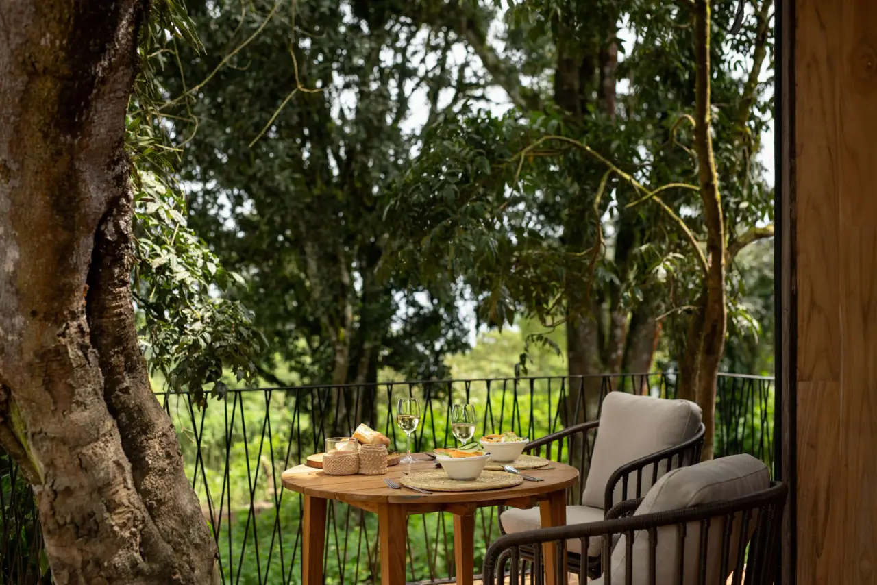 Private forest deck at Lemala Osonjoi set for an intimate meal with wine glasses beneath the tree canopy