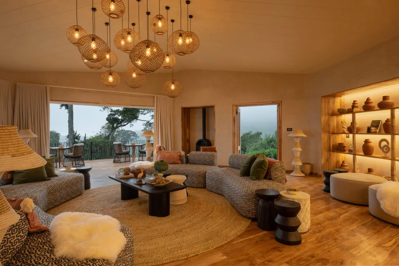 Lounge at Lemala Osonjoi with woven pendant lights and curved sofas opening onto a forest-view deck