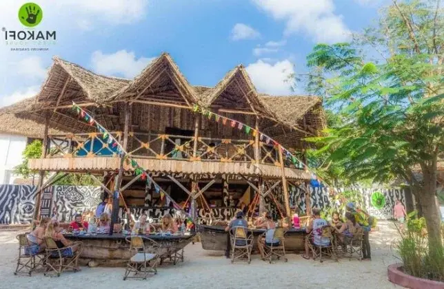 Makofi Guest House's open-air beachfront restaurant with colorful bunting and communal dining tables on the sand, Zanzibar