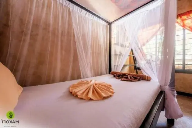 Guest room at Makofi Guest House with a sheer white mosquito net canopy over the bed and folded towel decor