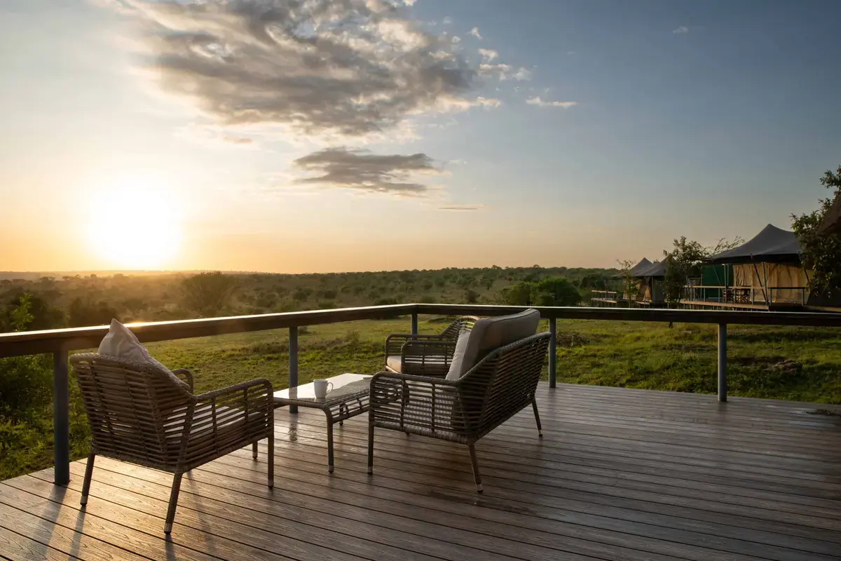 Wicker lounge seating on the sundowner deck at Mara Mara Tented Lodge overlooking the Serengeti plains at sunset