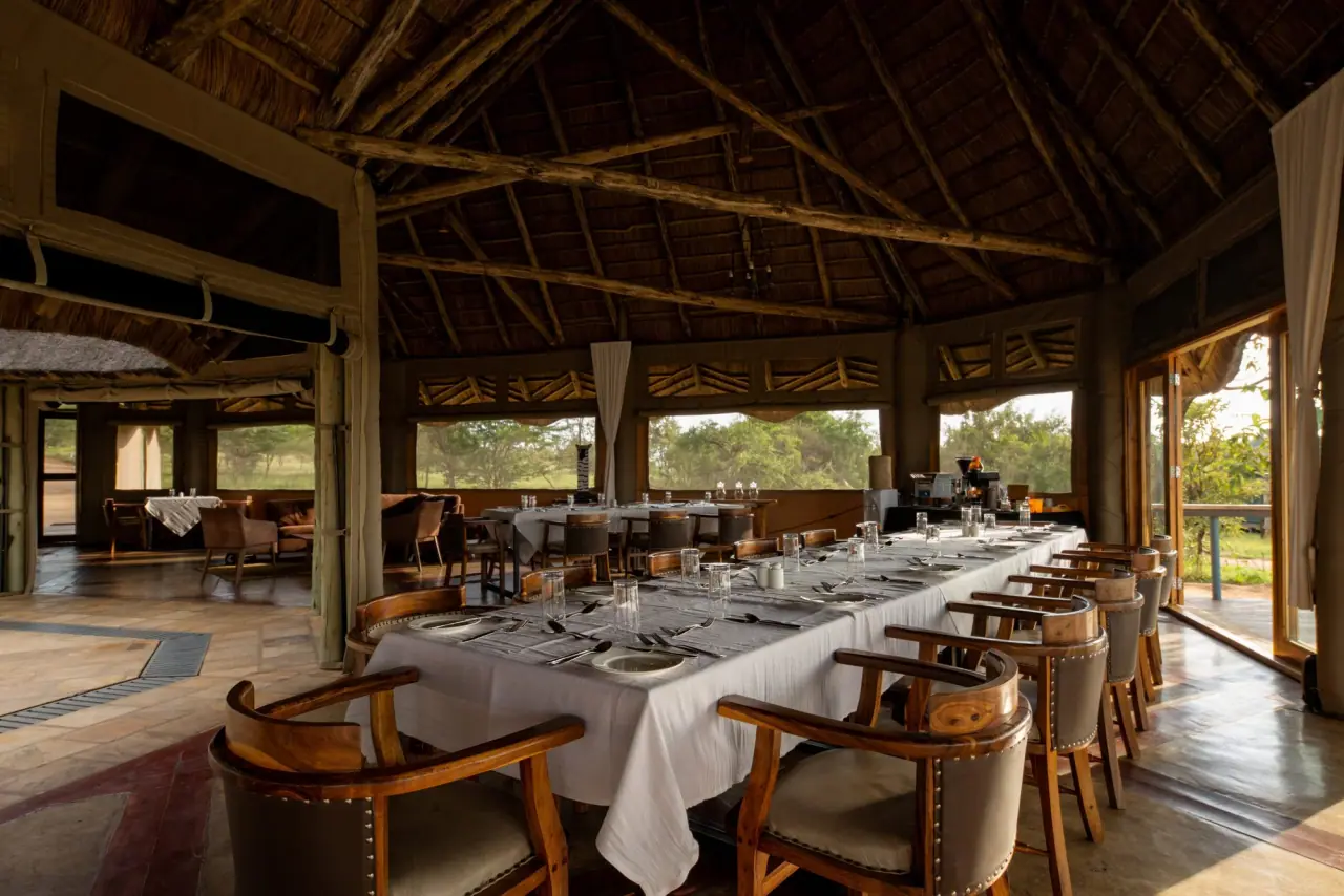Open-air dining room at Mara Mara Tented Lodge set for a group meal under a thatched roof