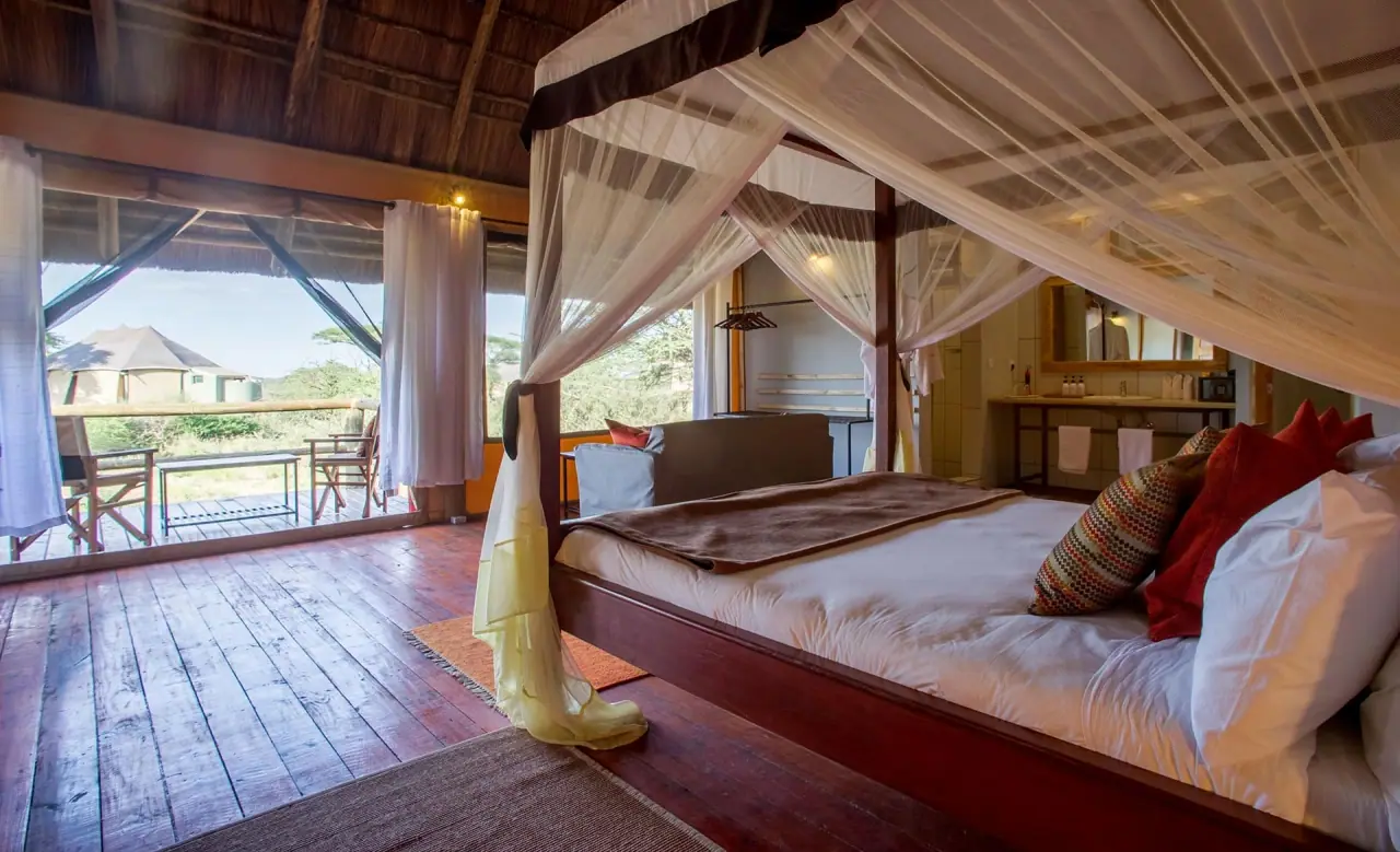 Four-poster bed under a mosquito net inside a guest tent at Masek Tented Lodge