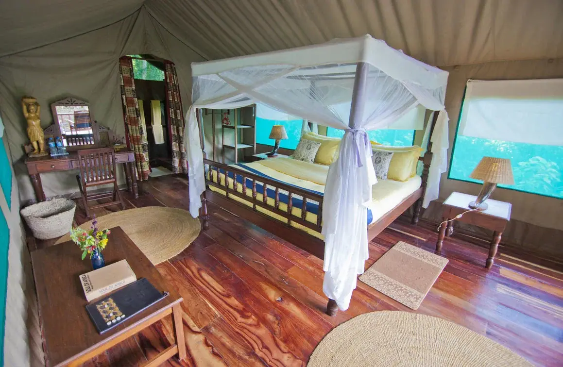Four-poster canopy bed in a guest tent at Mbali Mbali Gombe Tented Camp