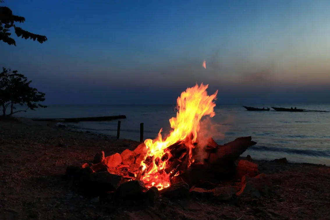 Beach bonfire at dusk on the shore of Lake Tanganyika at Mbali Mbali Gombe Tented Camp