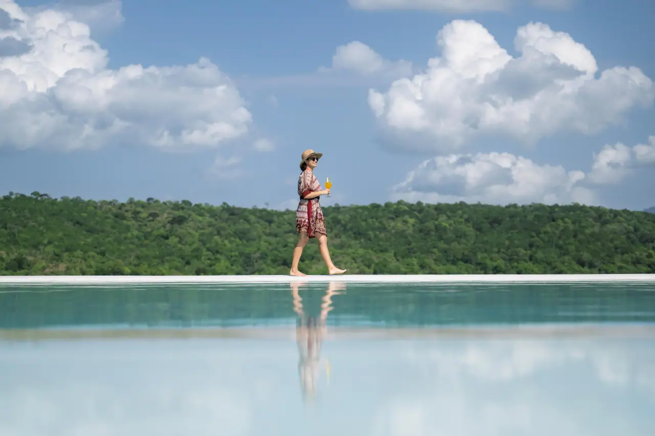 Guest walking along the edge of the infinity pool at Mikumi Wildlife Lodge overlooking the park