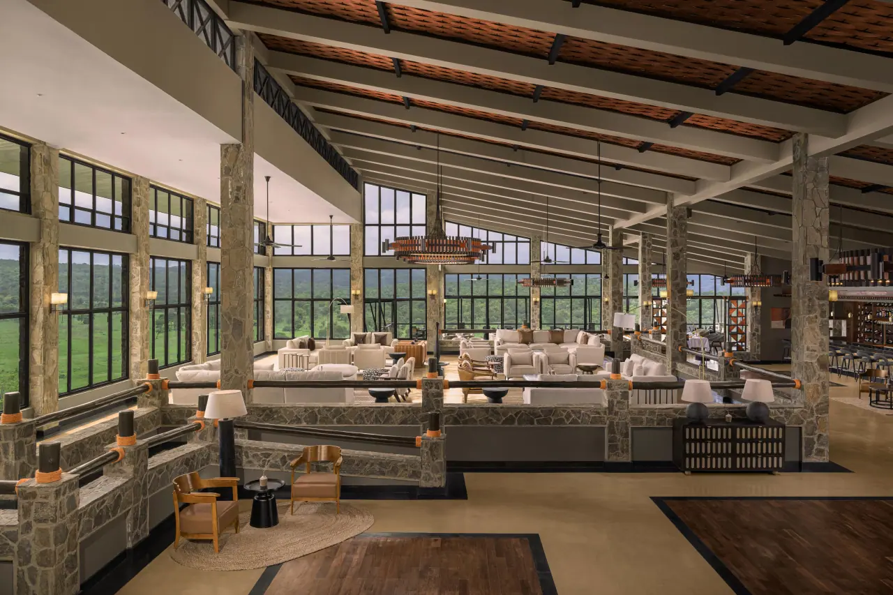 High-ceilinged lounge at Mikumi Wildlife Lodge with floor-to-ceiling windows over Mikumi National Park