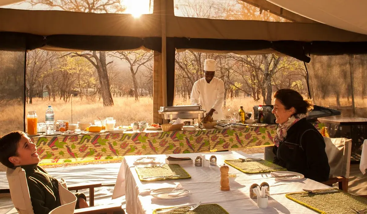 Chef serving breakfast to guests inside the mess tent at Ndutu Kati Kati Tented Camp