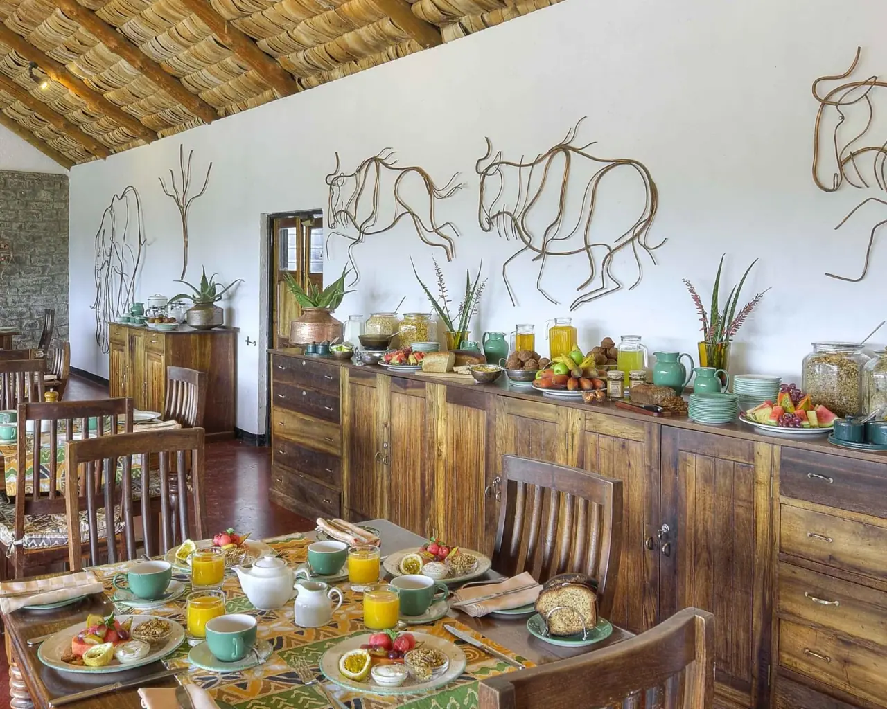 Breakfast buffet spread at Ndutu Safari Lodge decorated with wildebeest wire-art wall sculptures