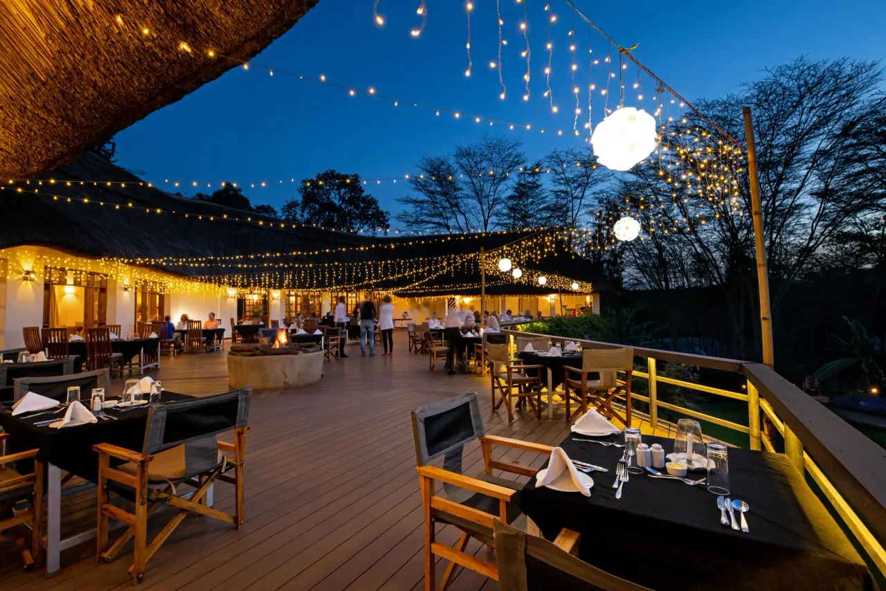 String-lit outdoor dining deck at Ngorongoro Farm House in the evening