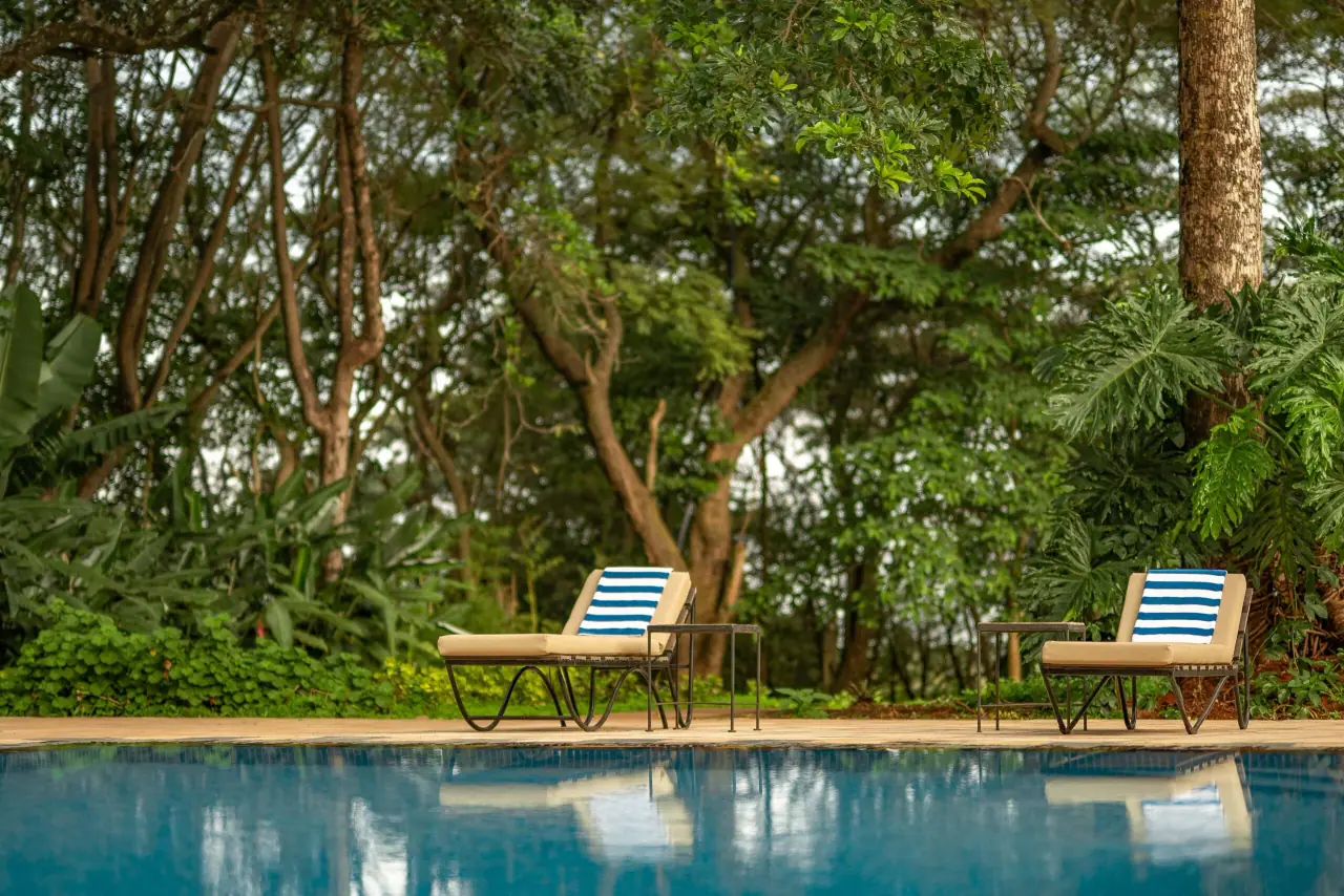 Poolside loungers shaded by trees at Ngorongoro Farm House