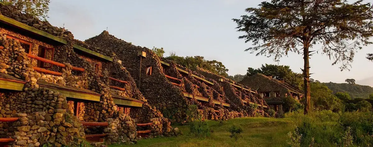 Stone-built guest rooms at Ngorongoro Serena Safari Lodge cut into the crater's forested rim at sunset